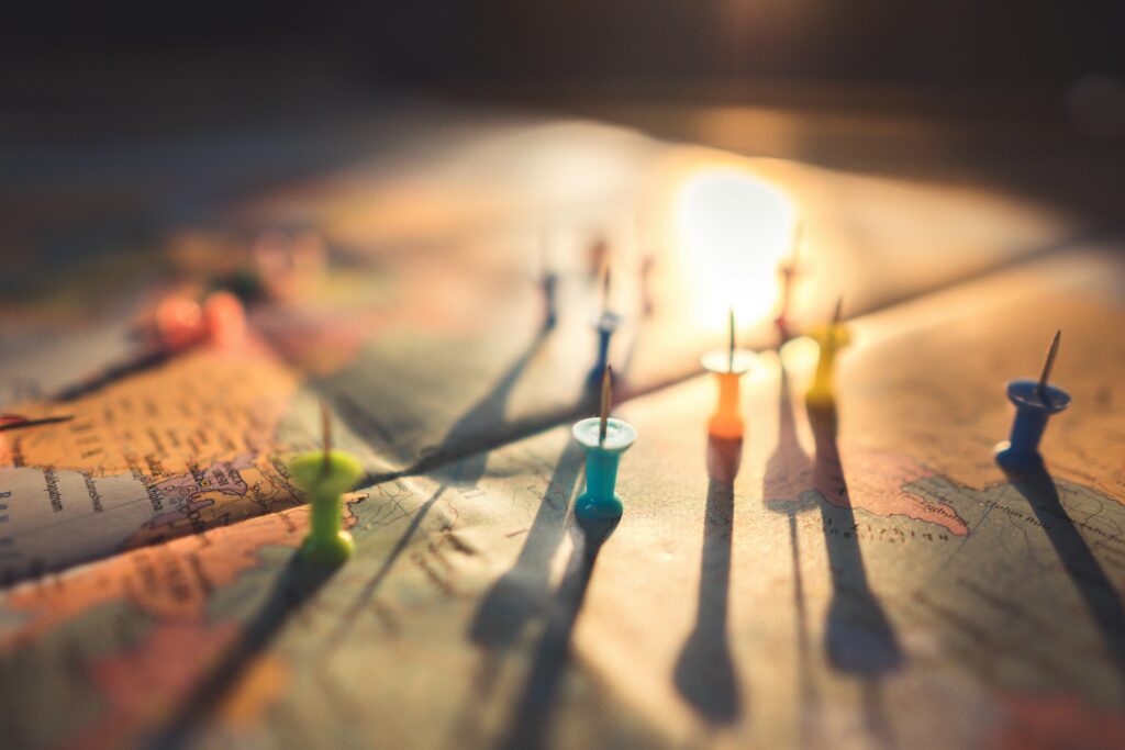 pexels-photo-1078850-1078850 A close-up view of colorful push pins casting shadows on a world map during sunset, highlighting global travel.