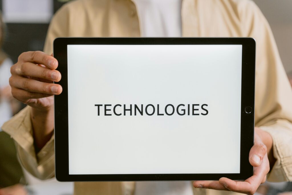 pexels-photo-6913311-6913311 Close-up of a person holding a tablet with the word 'Technologies' on the screen.